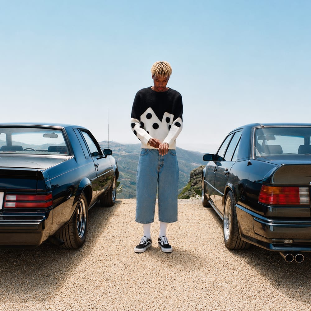 Person standing between vintage cars on open road street style photography
