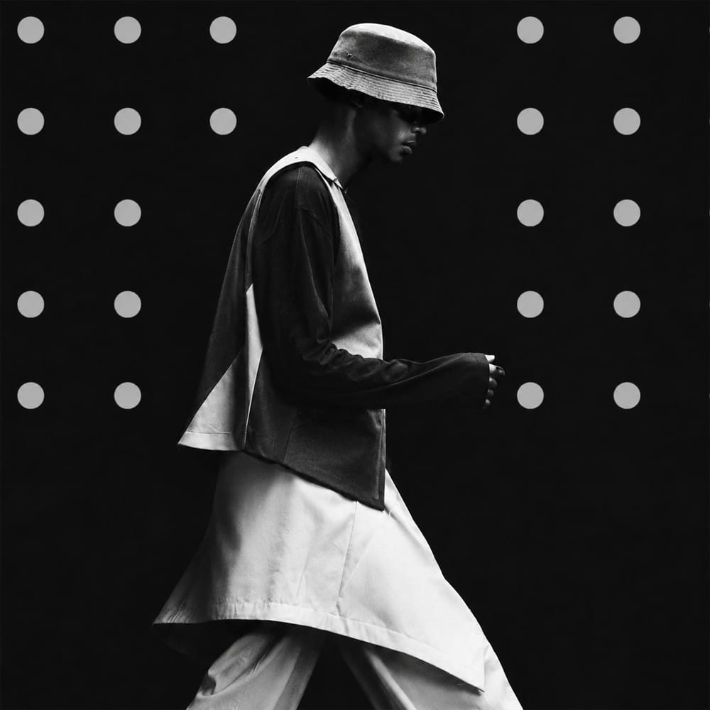 Black and white editorial portrait of person in bucket hat on dotted background