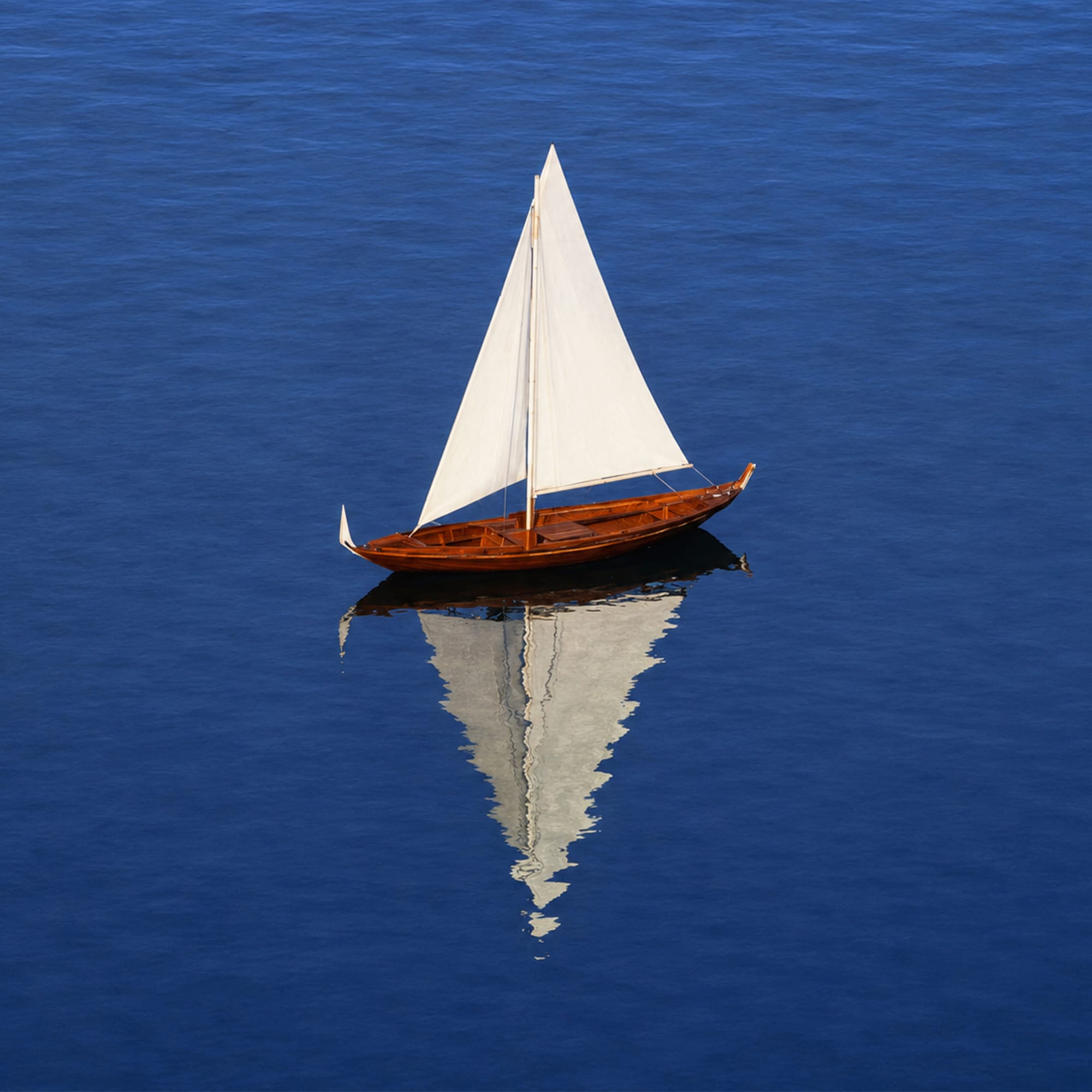 Small white sailboat on deep blue calm water minimal seascape photography