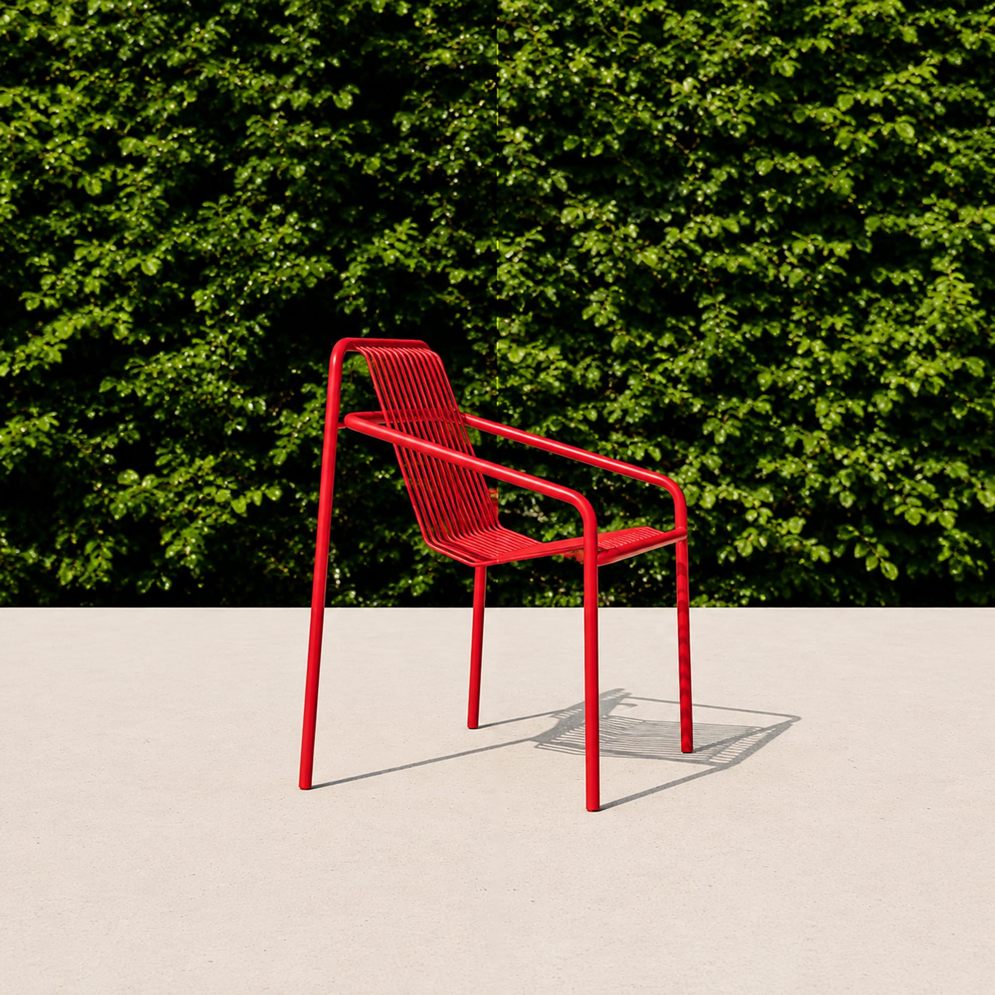 Bright red chair against lush green hedge wall minimal outdoor photography
